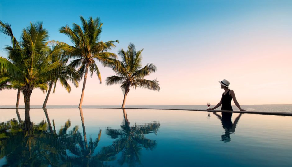 Swimming pool with palm trees, surrounded by scenic views as you rewild in Africa